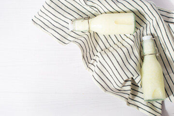 Filling with homemade kefir, buttermilk or yogurt with probiotics. Yogurt in a glass bottle on a white wooden background. Cold fermented milk drink with probiotics.