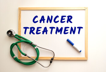 The text CANCER TREATMENT is written on a white office board. Nearby is a stethoscope.