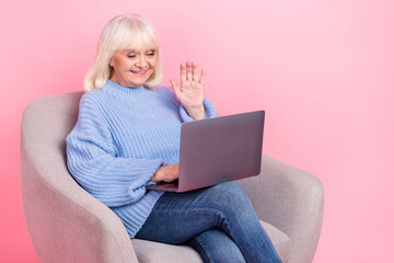 Naklejka premium Portrait of attractive cheerful grey-haired woman using laptop calling waving hi hello isolated over pink pastel color background