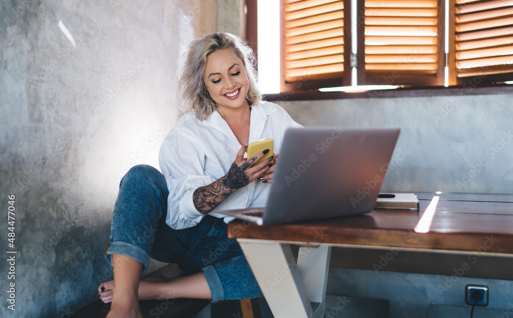 Poster smiling female generation z with laptop computer using modern cellular gadget for making online book