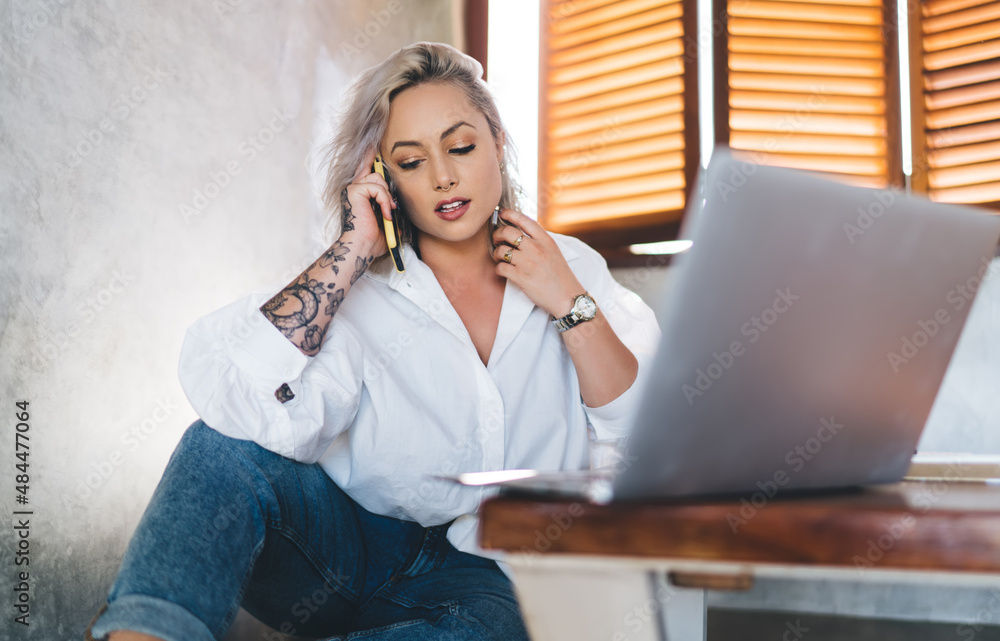 Poster millennial blonde woman with digital netbook technology using wireless connection on mobile phone fo
