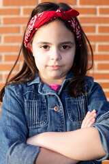 Portrait of little girl in powerful attitude. Future is feminine. Close up. Background of brick wall.