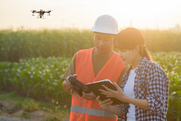 Male engineer  provide a consultation and instructing to smart farmer with drone spraying fertilizer and pesticide over farmland,High technology innovations and smart farming