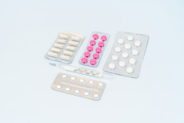 Capsules pills with thermometer and tablets in blister packaging. Isolated