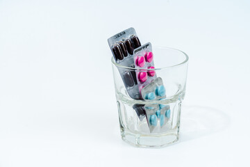 Capsules pills and tablets in blister packaging in glass. Isolated