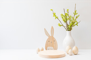 Empty round wooden podium for product presentation. Willow branches in a vase and easter eggs on a...