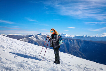 Fototapeta na wymiar Girl on hike goes up the top of the snowy mountain.