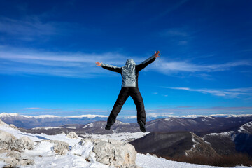 Hiker in the mountains jumps happy in the blue sky
