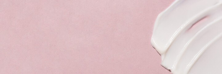 Smear of cream on a pink background.