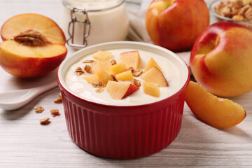 Delicious yogurt with fresh peach and granola on white wooden table