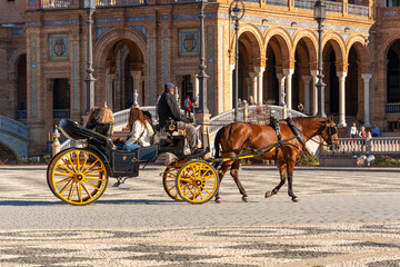 A group of female tourists enjoy a horse carriage ride through the Plaza de Espana, or Spanish...