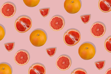Creative pattern with fresh whole and sliced grapefruit on bright pink background. Minimal fruit concept.