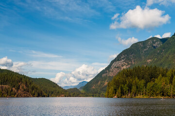 Fototapeta premium Summer day on the lake between forested mountains