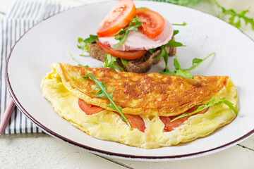 Breakfast. Omelette with tomatoes, cheese and sandwich with boiled sausage.  Frittata - italian omelet.
