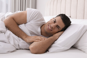 Happy man lying in bed at home