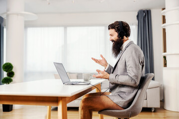 A businessman in vest and underwear having online meeting at home.