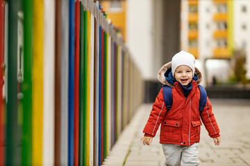 A happy kindergarten child with a schoolbag rushing to kindergarten.