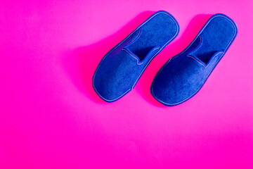 Home comfort with blue velvet slippers. Pink background. Copy space