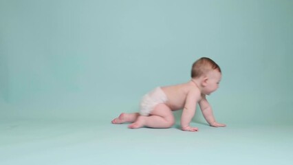 Happy toddler baby crawling on studio blue background. Funny child boy at the age of six months with a smile on his face, copy space - Powered by Adobe