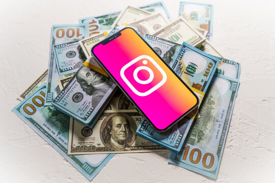 Berlin, Germany - February 02, 2022: Money and smartphone displaying the Instagram logo. Social media. Instagram is a photo-sharing app for smartphones