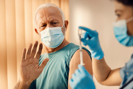 A Senior Man In Hospital Is Against Covid 19 Vaccine And Showing Stop Gesture. 