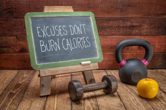 excuses do not burn calories inspirational concept -  white chalk text on a slate blackboard sign against weathered rustic wood with a dumbbell and kettlebell