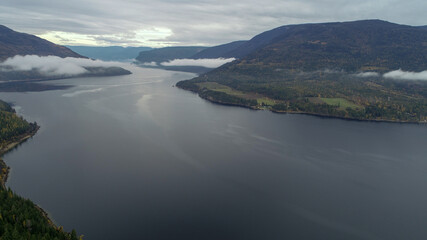 A Beautiful Lake Set In The Mountains Is Accented By The Changing Fall Leaves Of The Trees.
