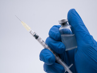 Hand close up holding syringe and vaccine bottle - 484495220