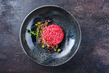 Modern style gourmet tartar raw from beef filet with capers and amarena cherry served with truffle...
