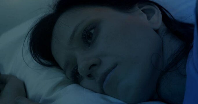 Woman lying in bed at night suffering from severe depression and anxiety suffers from insomnia