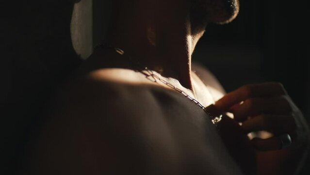 man touching a pendant on his neck close-up