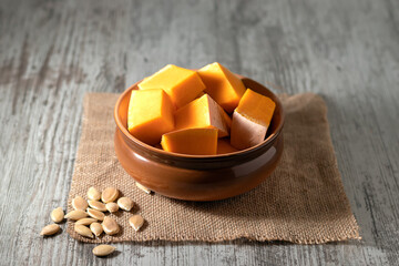 raw pumpkin prepared for cooking and pumpkin seeds on a wooden table.