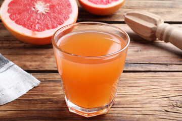 Tasty freshly made grapefruit juice on wooden table
