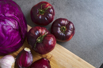 Fresh fruits and vegetables. Organic, red onions, red cabbage, purple tomatoes. Dark heirloom tomatoes. Farmer's market winter harvest. Purple vegetables.