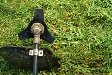 Lawn trimmer with a three-bladed knife on the trimmed grass