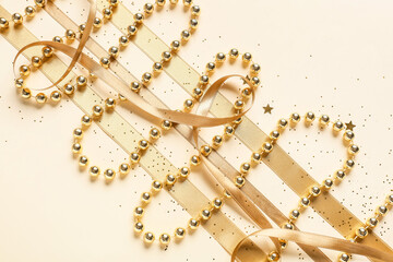 Golden ribbons and beads with confetti on light background