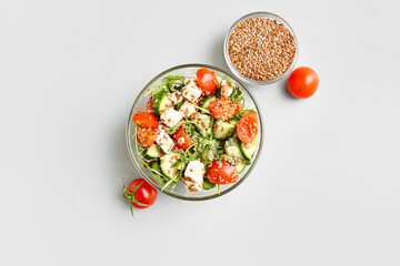 Bowl with healthy vegetable salad and flax seeds on light background