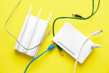 Wi-Fi router with antennas and network cables on color background