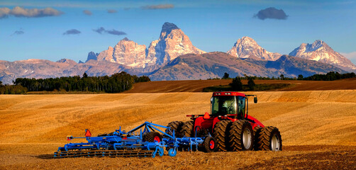 Tractor Farming Ground Harvesting Crops in Fall Autumn Teton Mountains Rugged