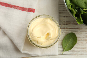 Jar of delicious mayonnaise and fresh spinach on white wooden table, flat lay