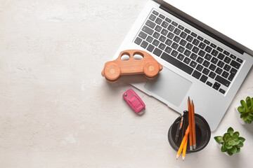 Laptop with wooden car, key and stationery on white background - Powered by Adobe