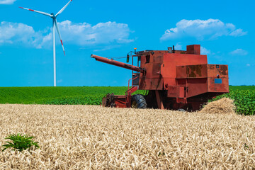 Harvester harvests ripe wheat on yellow rural field on a summer sunny day. Landscape of an endless...