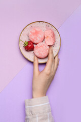 Woman eating delicious mochi on color background