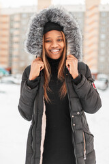 Happy portrait of beautiful young stylish black african woman with hat in fashionable winter jacket...