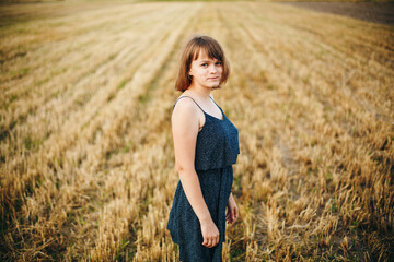 A beautiful girl and a field on which they threshed grain. Woman after harvest. Girl and yellow field

