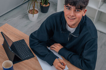 teen boy at home studying with computer or tablet