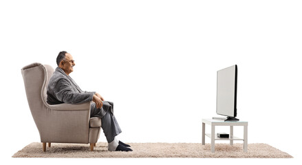 Profile shot of a mature man in a bathrobe sitting in an armchair and watching tv - Powered by Adobe