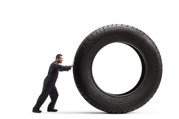 Full length profile shot of a mechanic pushing a big vehicle tire