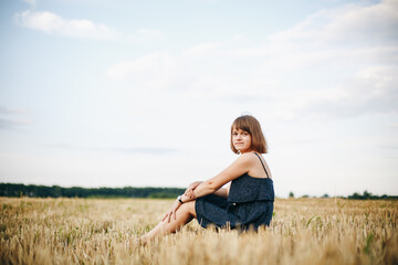 Naklejka na ściany i meble A beautiful girl and a field on which they threshed grain. Woman after harvest. Girl and yellow field 