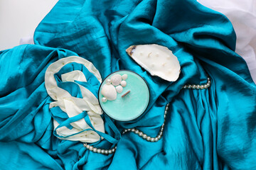 gift concept. Marine theme. handmade aroma candle in a glass on a background of turquoise silk. natural soy wax. 